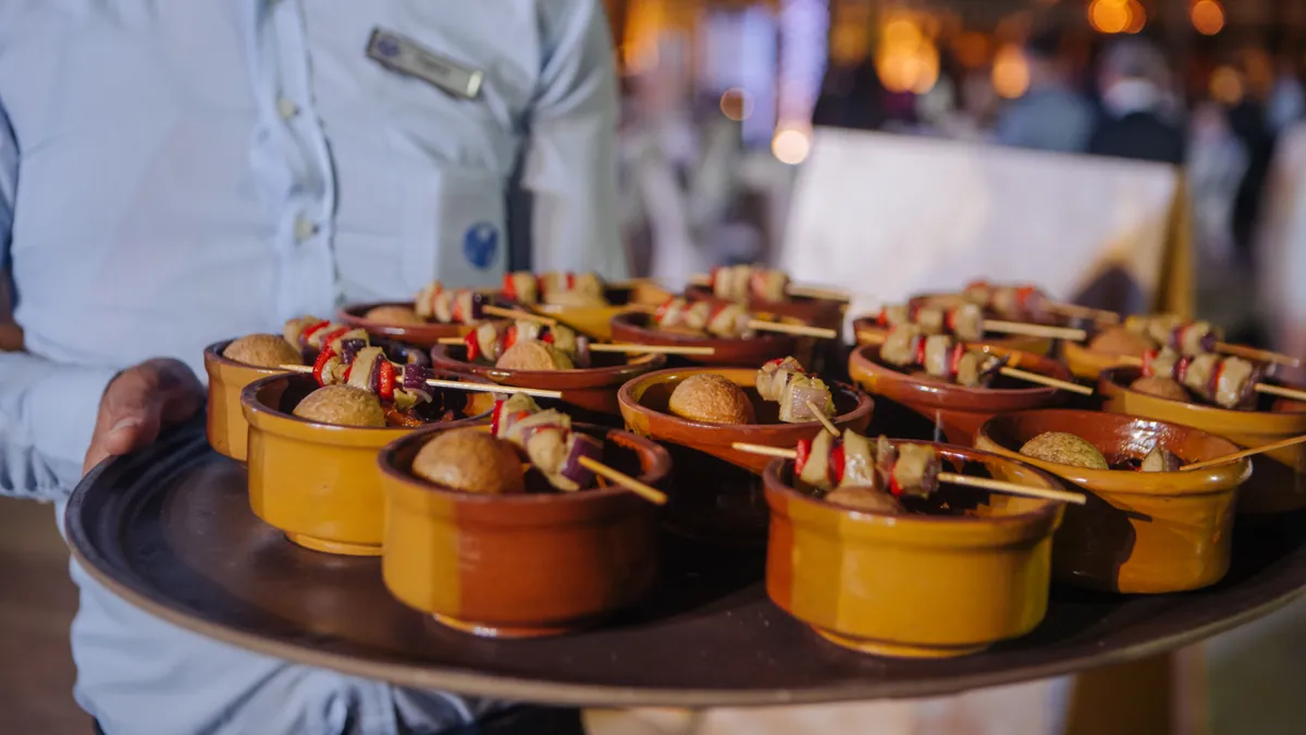 A person holds a tray of small orange dishes featuring skewers of cultivated meat lying across the top.